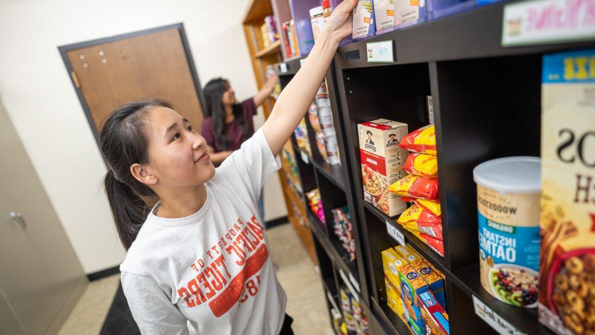 A student restocks shelves at the Pacific Food Pantry